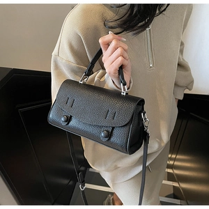 Detail of black textured leather handbag with silver hardware and adjustable strap