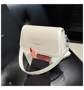 Detail of white PU leather crossbody bag with woven texture and silver hardware