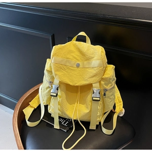 Detail of bright yellow wrinkled nylon backpack with buckle closure and side pockets