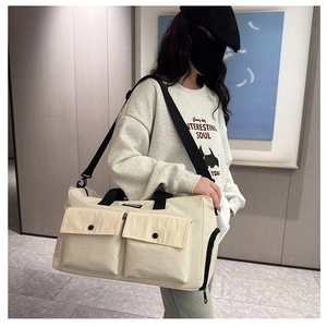 Detail of cream-white travel bag featuring cargo pockets and adjustable black strap