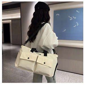 Action shot of large beige canvas travel bag with black straps and spacious front pockets