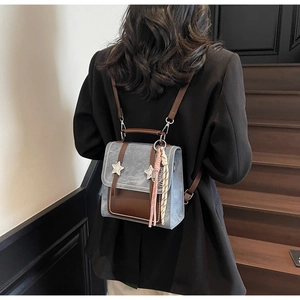 Sac à dos bleu gris à la mode porté avec rivets étoiles et détails de glands