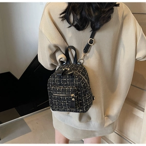 Détail d'un sac à dos en tweed noir et doré avec poignée en cuir et bretelles réglables
