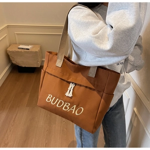 Detail of caramel canvas tote bag featuring BUDBAO embroidery and side storage pocket