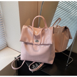 Detalle de la mochila rosa claro con grabado de cocodrilo, cierre giratorio y asa superior