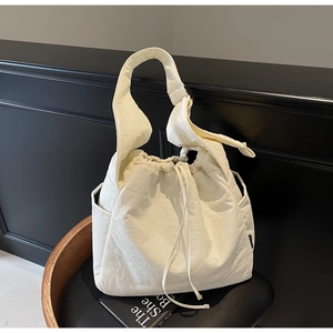 Detail of a creamy white nylon tote bag with drawstring closure on a black chair