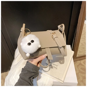Detail of dark khaki lychee leather crossbody bag with cute white plush ball charm