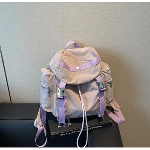 Detail of waterproof nylon backpack with beige body and purple contrast flap and buckles