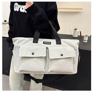 Detail of canvas travel bag featuring dual front pockets with black snap buttons