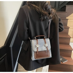Détail du petit sac carré rétro avec étoiles et garniture en cuir brun sur corps gris bleu