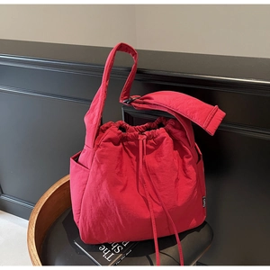 Detail of red drawstring bucket bag with textured nylon fabric on black leather chair