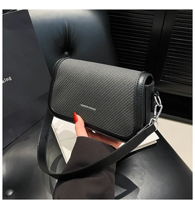 Detail of the woven texture and black leather trim on a gray crossbody flap bag