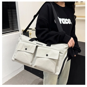 Close-up of beige travel bag with large front snap pockets and adjustable shoulder strap