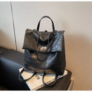 Detalle de mochila negra con relieve de cocodrilo y cierre de giro metálico plateado