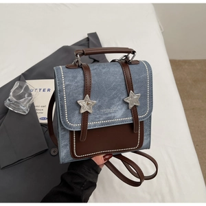Détail d'un sac à dos en denim bleu clair avec boucle étoile et coutures contrastées