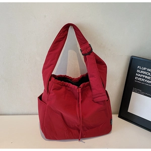 Detail of red quilted shoulder bag featuring soft nylon texture and adjustable wide strap
