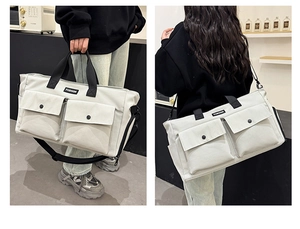 Detail of travel bag showing front flap pockets and adjustable black crossbody strap