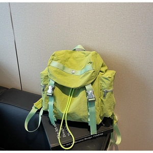 Detail of bright green nylon backpack with silver buckle and drawstrings on black background