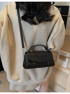 Minimalist black lychee pattern leather crossbody bag shown on a model in a warm interior
