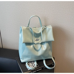 Detalle de la mochila verde menta con textura de cocodrilo y cierre giratorio de metal