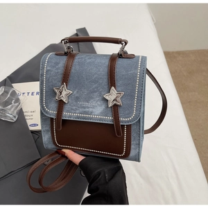 Détail du mini sac à dos en denim et cuir marron avec boucles en étoile argentées