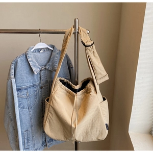 Detail of khaki nylon shoulder bag featuring side pocket and adjustable drawstring
