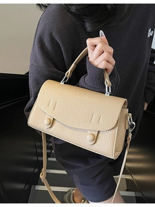 Minimalist beige pebble leather crossbody bag with dual buttons and adjustable strap
