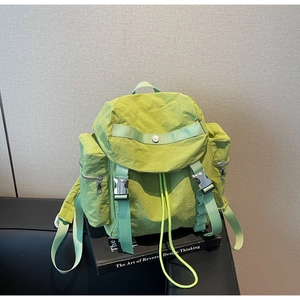 Detail of light green nylon backpack featuring textured fabric and metal buckle closure