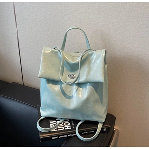 Detalle de mochila verde menta con relieve de cocodrilo, cierre giratorio plateado y asa