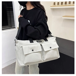 Detail of white travel bag with dual front flap pockets and fashion strap in use