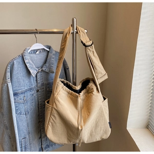 Detail view of khaki drawstring tote bag featuring a side pocket and adjustable wide strap