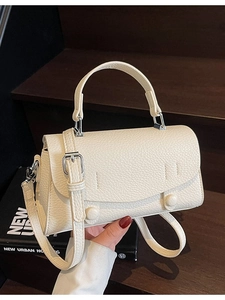 Minimalist beige pebble leather crossbody bag with top handle and decorative round buckle