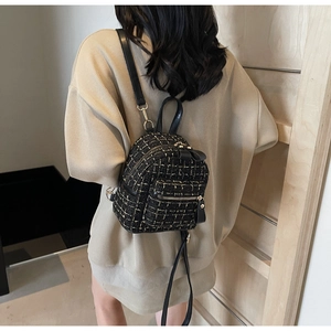Détail d'un mini sac à dos en tweed noir chic avec fils dorés et bretelles en cuir