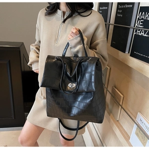 Detalle de la mochila de cuero negro con estampado de cocodrilo y cierre giratorio de metal
