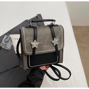 Détail d'un mini sac à dos bicolore gris et noir avec clous en étoile et rivets argentés