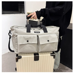 Detail view of a gray travel bag with front buckle pockets mounted on a suitcase