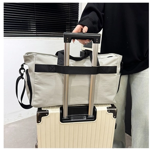 Travel duffel bag featuring back strap for secure attachment to luggage trolley handles