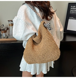 Détail d'un grand sac cabas en paille avec anses rayées noir et blanc sur un mannequin