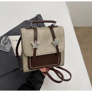 Détail du sac à dos en cuir gris et marron avec boucles étoiles et coutures perlées