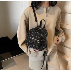 Détail du tissu en tweed et de la bandoulière d'un mini sac à dos à carreaux porté