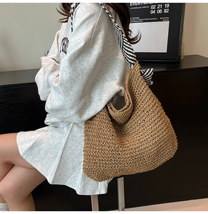 Détail du sac hobo en paille marron avec bandoulière tissée à rayures noires et blanches