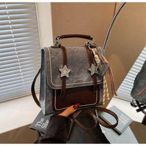 Détail du sac à dos en denim vintage avec finitions en cuir et ornements en métal étoilé