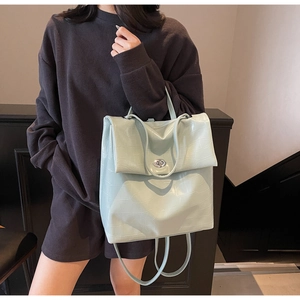 Detalle de mochila verde menta con textura de cocodrilo y cierre de giro plateado