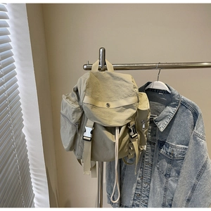 Detail of beige nylon backpack with silver buckles and drawstring closure in casual style