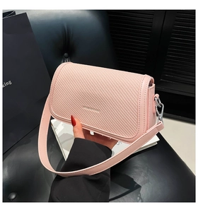 Detail of pink crossbody bag with woven texture, silver logo, and leather strap