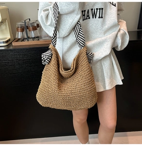 Détail d'un sac hobo en paille tressée main avec bandoulière rayée noir et blanc