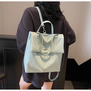 Detalle de mochila verde menta con grabado de cocodrilo, cierre plateado y asa resistente