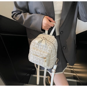 Détail du mini sac à dos en tweed blanc et doré avec poignée en cuir et zips dorés