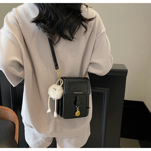 Close-up of black PU leather crossbody bag with fluffy charm and Fashion & Bags text