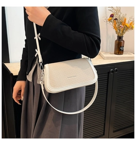 Detail of off-white woven shoulder bag with silver hardware and fashion text